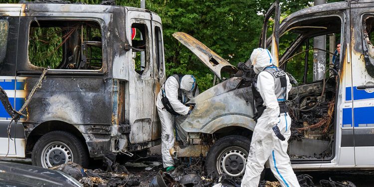 22.06.2022, Bayern, München: Ermittler der Spurensicherung arbeiten an einem Polizeiauto, das in der Nacht ausgebrannt ist. Die Mannschaftsbusse der Bundesbereitschaftspolizei stehen vor einem Hotel, in dem Polizisten für den G7-Gipfel untergebracht sind. Die Ermittler gehen von Brandstiftung aus. Foto: Peter Kneffel/dpa +++ dpa-Bildfunk +++