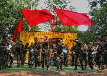 This picture taken on April 15, 2022 shows members of the "Peacock Generation" activist troupe, some of whom are dressed as part of the "People's Defence Forces" (PDF), waving Yangon Student Union flags during a traditional "Thangyat" performance in Kayin state. - A troupe of Myanmar folk singers and satirists are taking their new show on a jungle tour, hoping to rally anti-coup fighters far from their families with barbs against the junta and jokes about home. (Photo by AFP) / TO GO WITH Myanmar-military-politics-coup-religion, FOCUS